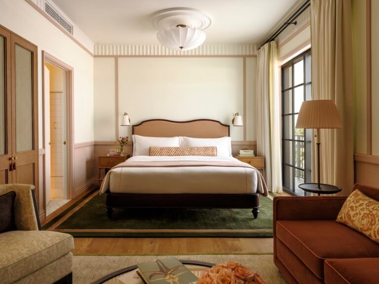 Nora Hotel guest room with pink wall trim, a green rug and a window-side sitting area — غرفة بفندق نورا بألواح وردية وسجادة خضراء وجلسة قرب النافذة