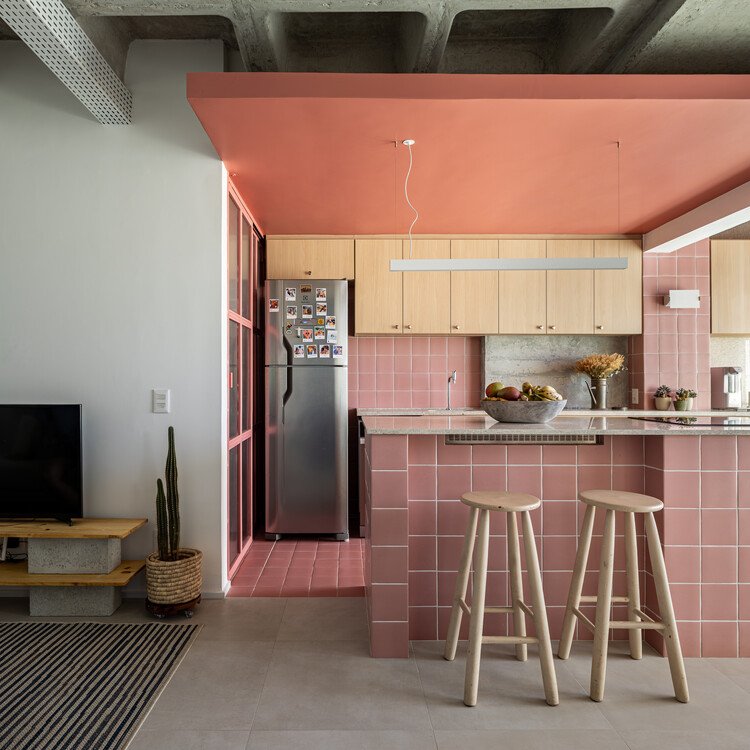 Pink kitchen counter and timber cabinets beneath the exposed concrete ceiling in ABC Apartment