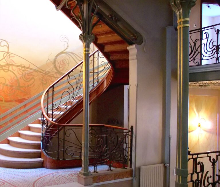 Curving iron columns and balustrades connect the staircase, mosaic floor and painted walls of Hôtel Tassel in Brussels.