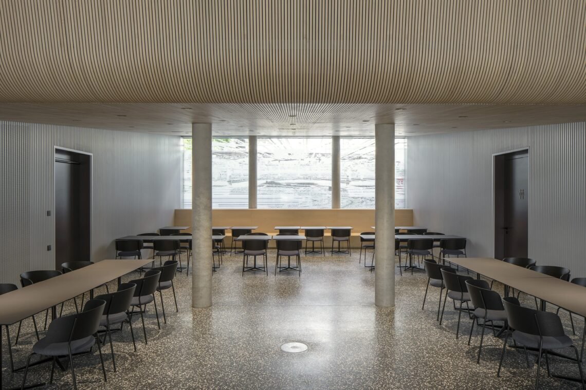 The cafeteria combines freestanding tables with a continuous perimeter bench.