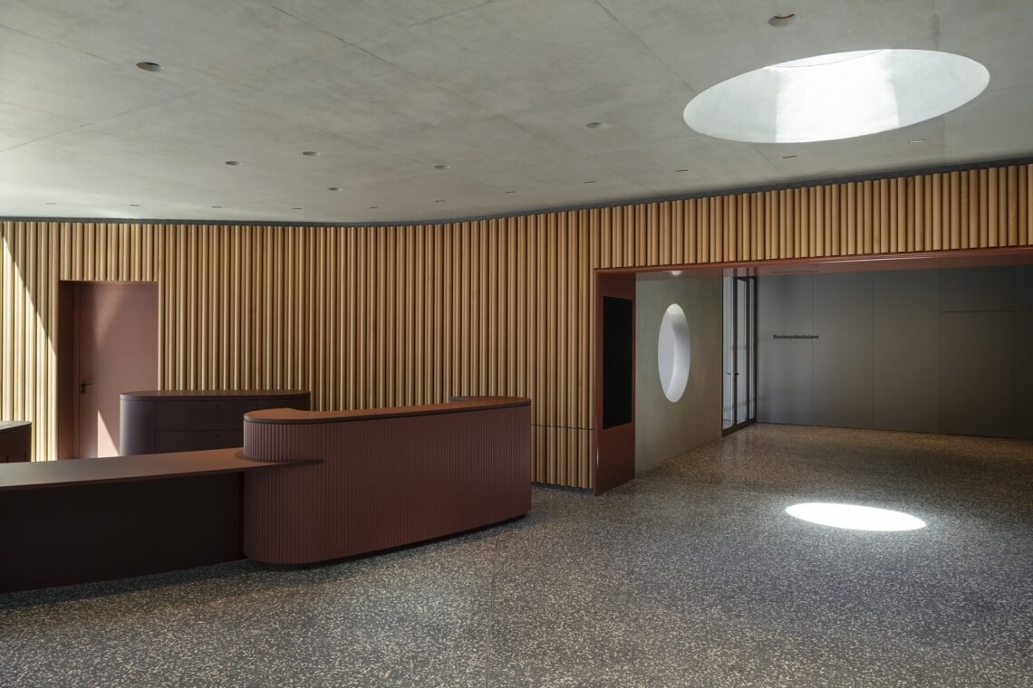 A curved reception counter beneath a circular rooflight.