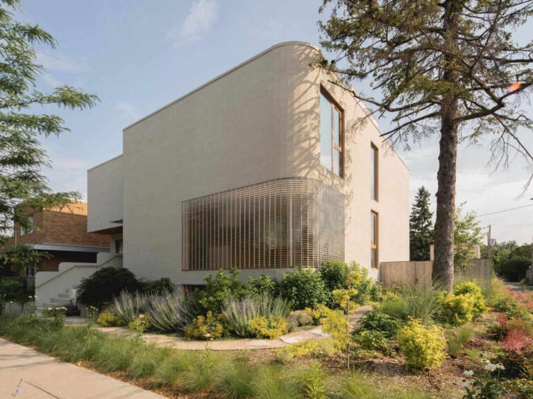 Curved glass-brick corner and pale masonry of The Lens house in Montreal