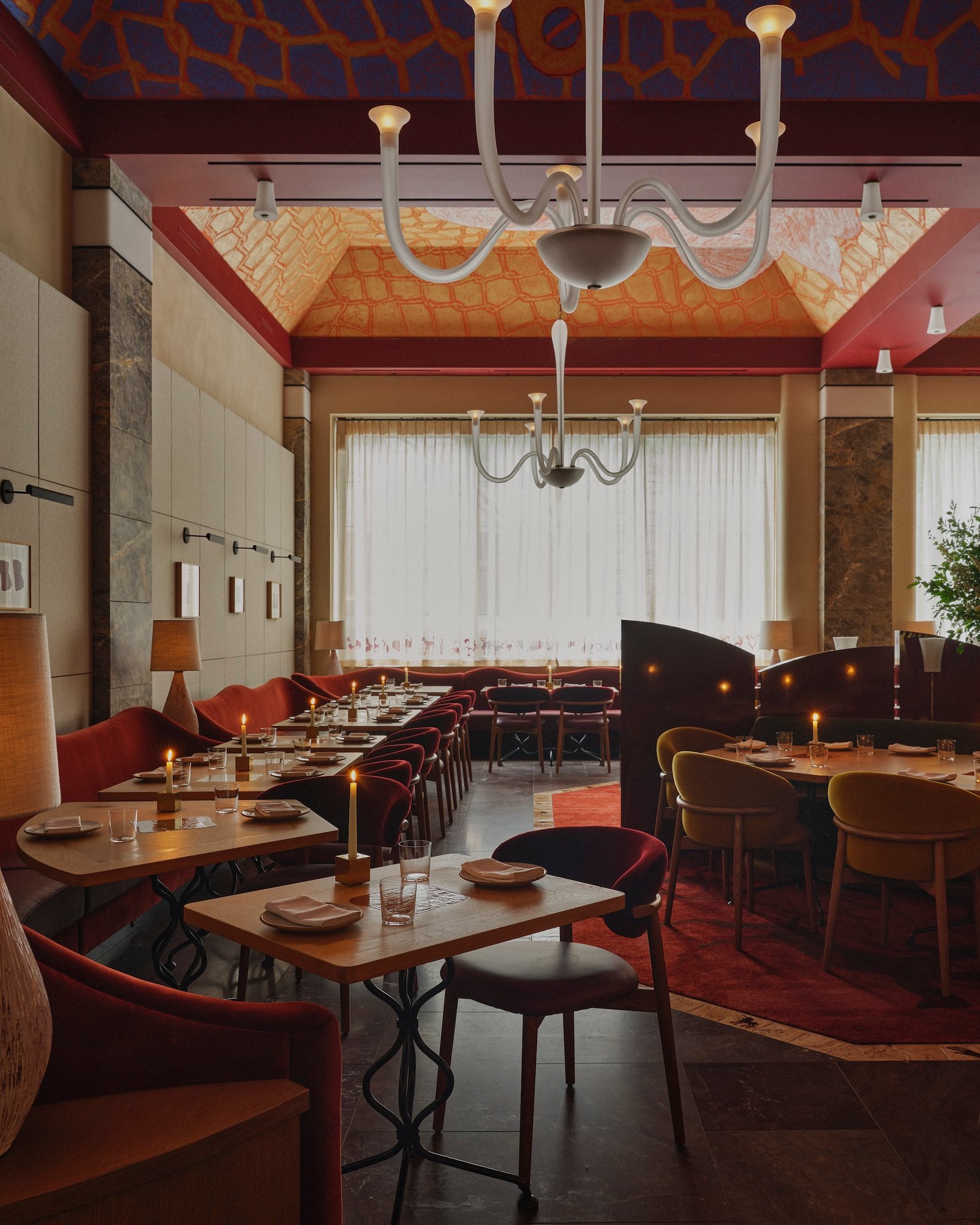 Dining tables and curved red screens beneath Humm’s painted ceiling