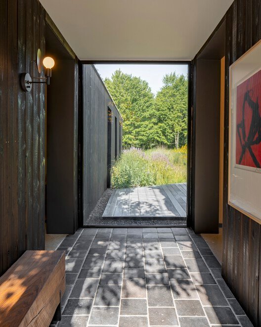 Glazed passage frames planting between the darker building volumes.