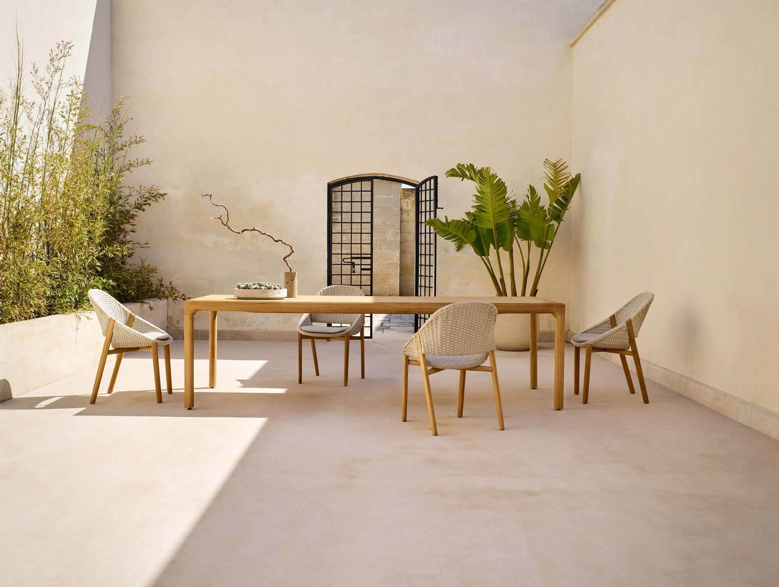 ELIO armchairs placed around a rectangular outdoor dining table