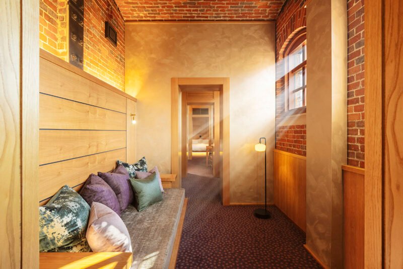 Living room with timber wall panels, a sofa and exposed brickwork above