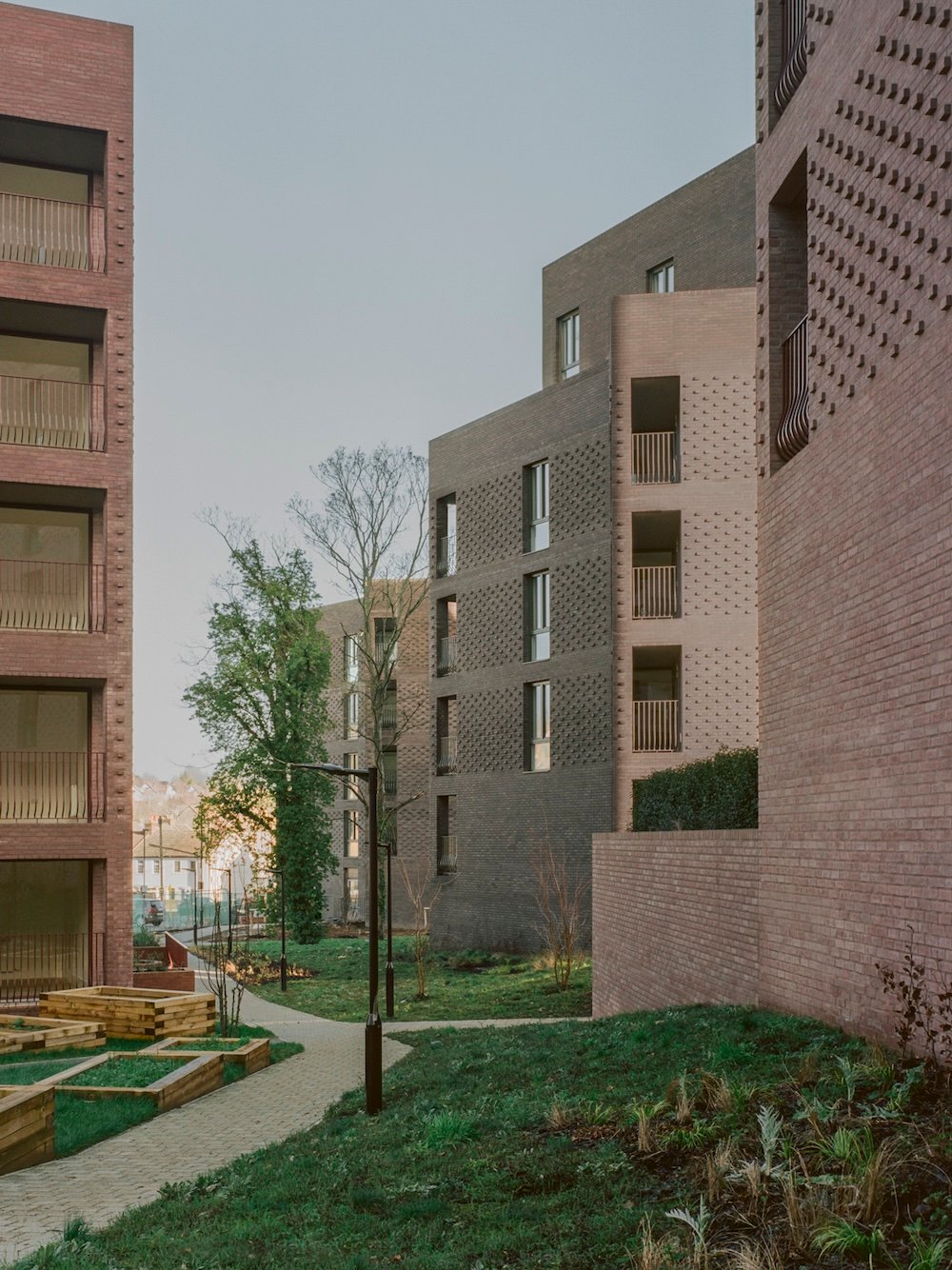 Brick housing blocks beside a winding planted path at Lion Green Road