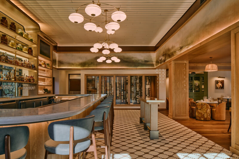 Blue bar stools follow the counter, while a patterned mosaic marks the bar floor.
