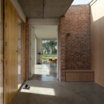 Brick walls, timber-faced doors and overhead daylight along the interior sequence of Laois House