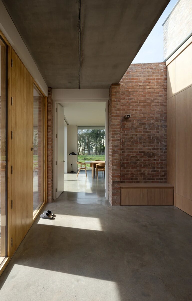 Brick walls, timber-faced doors and overhead daylight along the interior sequence of Laois House