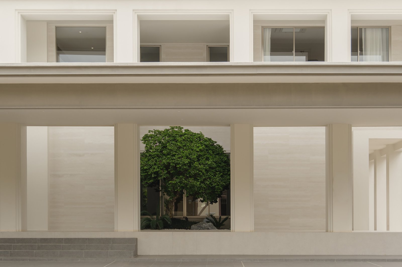 Interior passage framing a courtyard tree at Prukpirom House