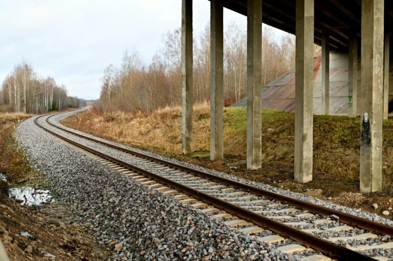 Railway tracks beneath concrete bridge piers; illustrative image, not the Tucson project. © Andres Siimon / Unsplash.