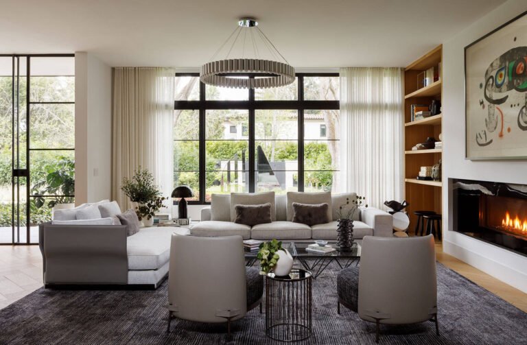 Atherton Residence living room with art above the fireplace, pale seating and timber display shelving