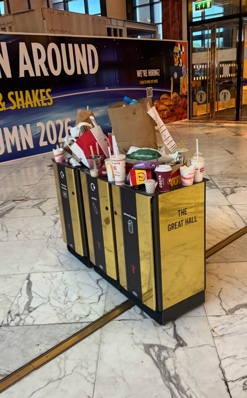 Cups, containers and bags resting on top of an indoor waste sorting station