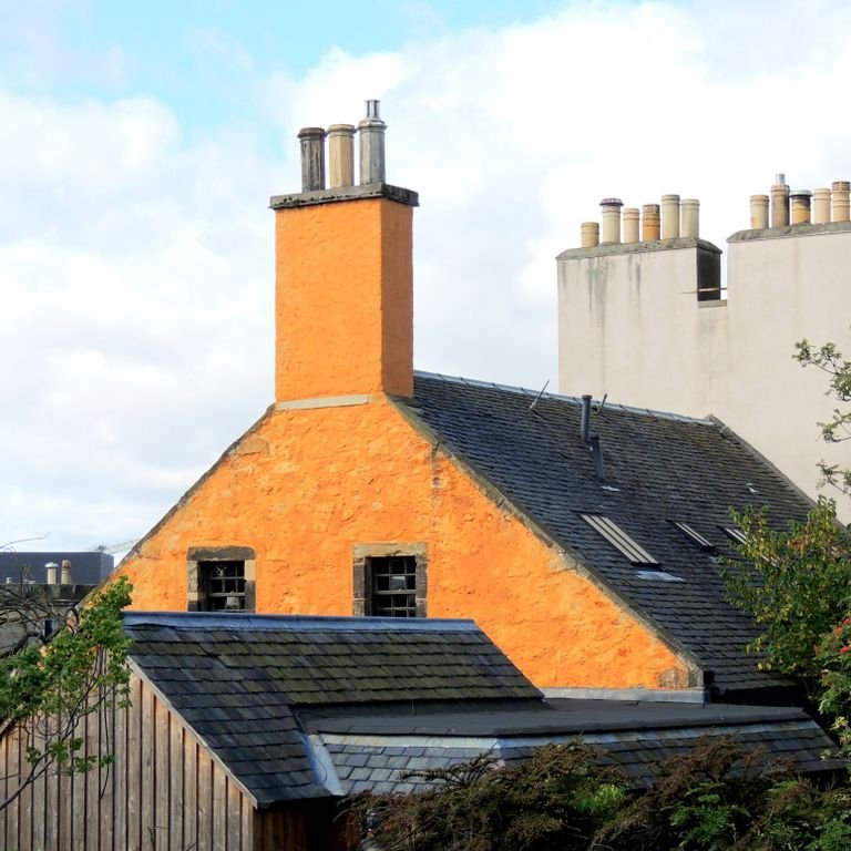 Yellow house with roof chimneys against a clear sky in Edinburgh, Scotland.