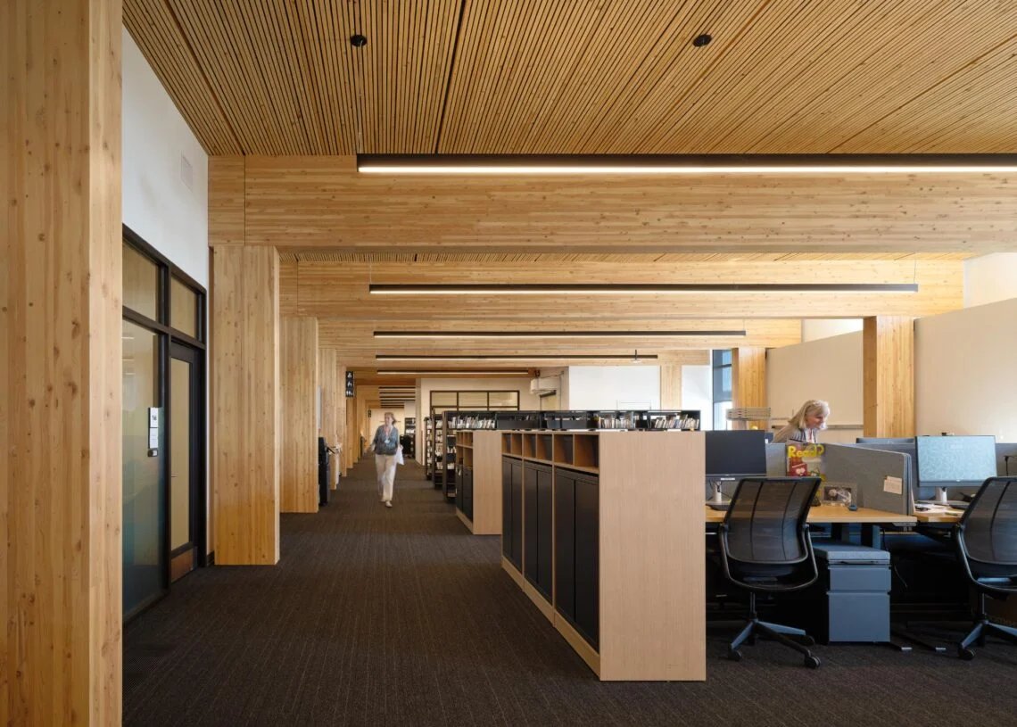 تحدد فواصل المكاتب محطات العمل أسفل السقف الخشبي المكشوف.