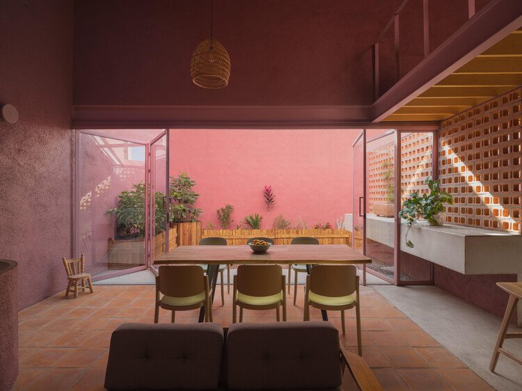 Open glazing connects the dining table to the enclosed planted courtyard