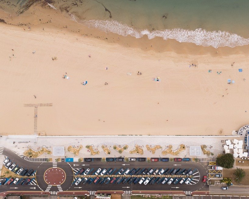 Aerial view of the Comillas promenade between the town, planted pockets and sandy beach