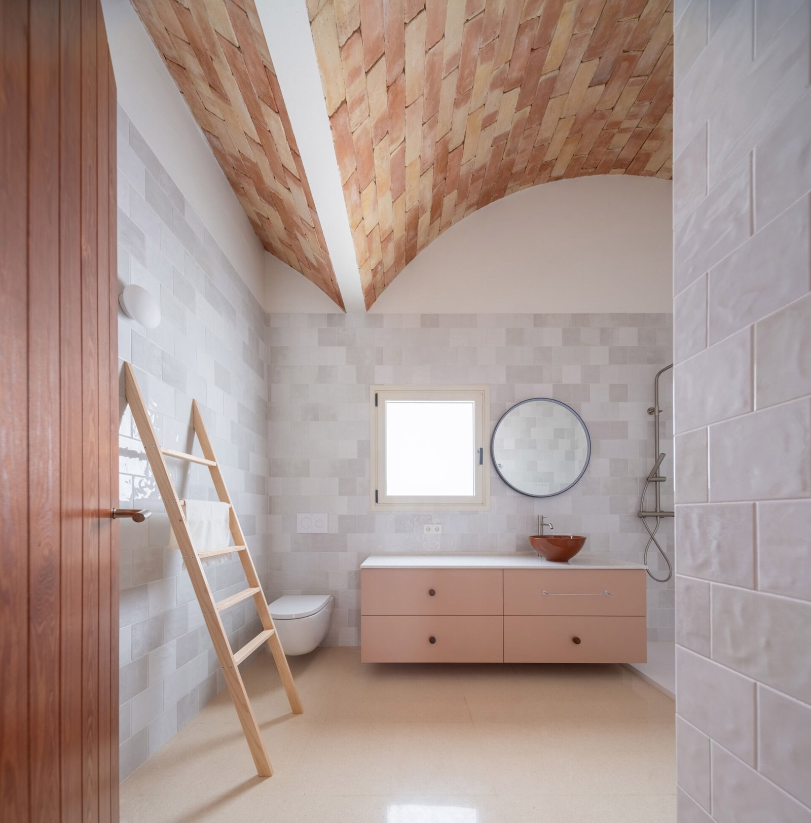 The bathroom brings tiled surfaces beneath the exposed brick ceiling.