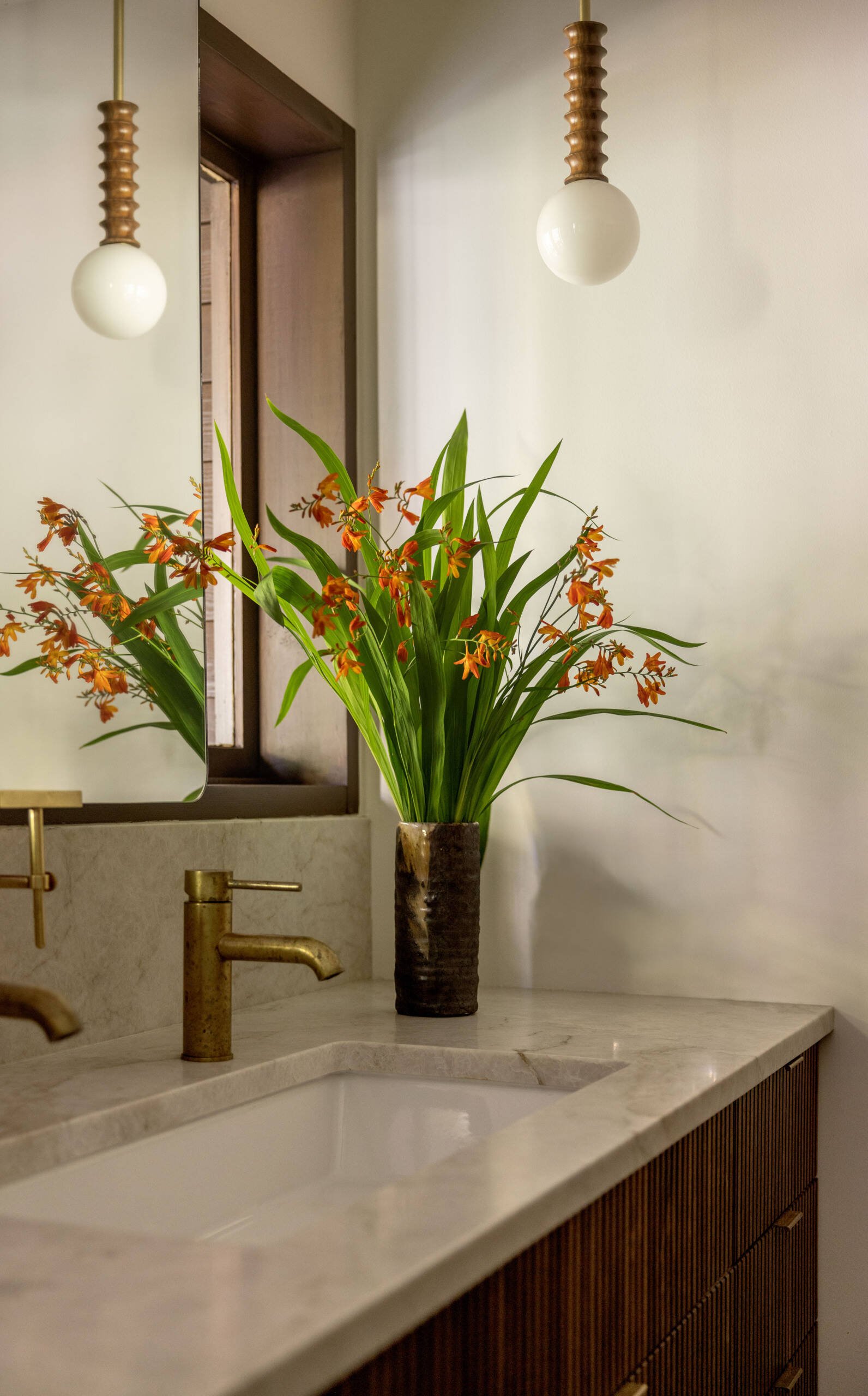 Mirror, stone surface and pendant light at the vanity edge
