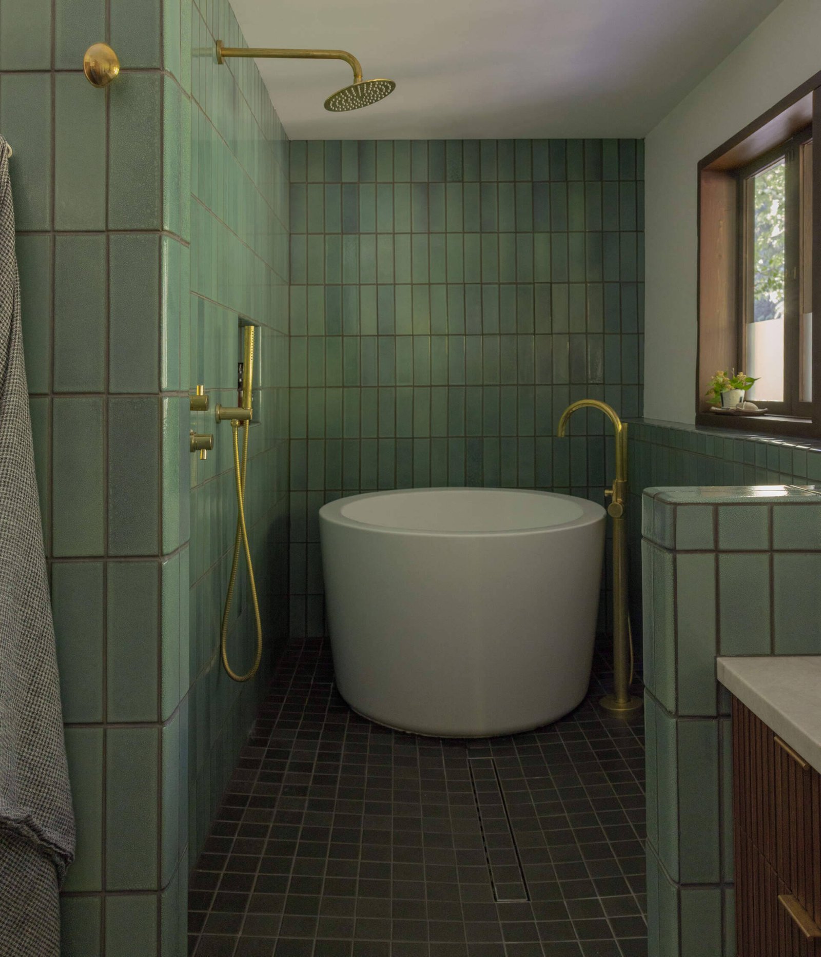 Green tiles define the wet room and freestanding bathtub