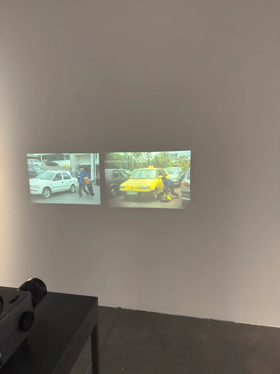 Two adjacent projected images showing vehicles and people on a street, on a gallery wall at Hayy Jameel.