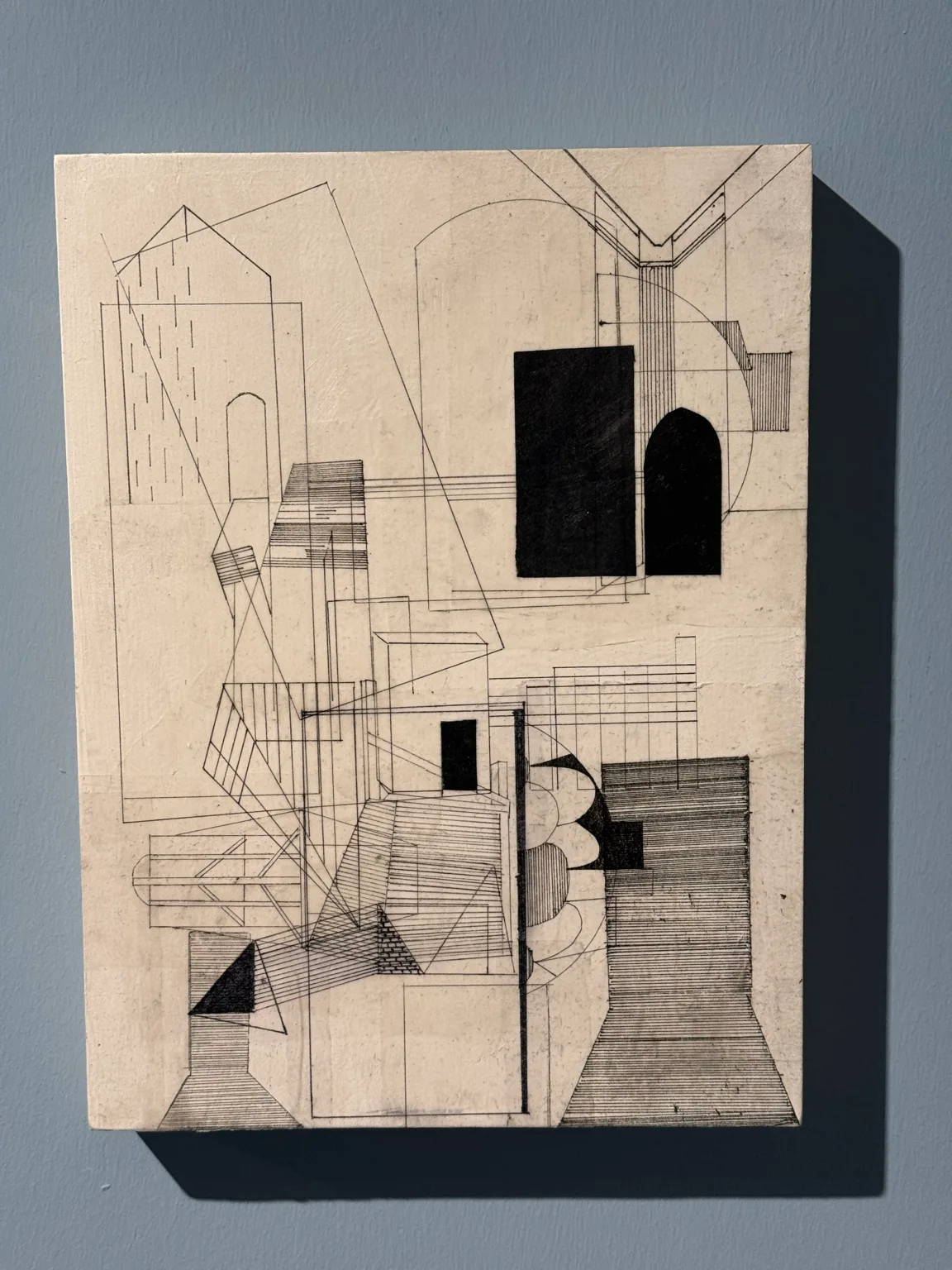 An artwork combining architectural line drawings, geometric forms and black shapes on a pale surface at Hayy Jameel.