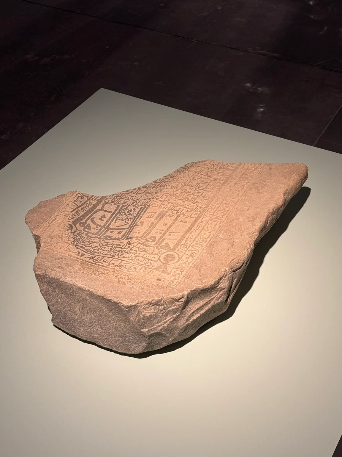 A stone slab bearing carved geometric and calligraphic decoration displayed on a plinth at Hayy Jameel.