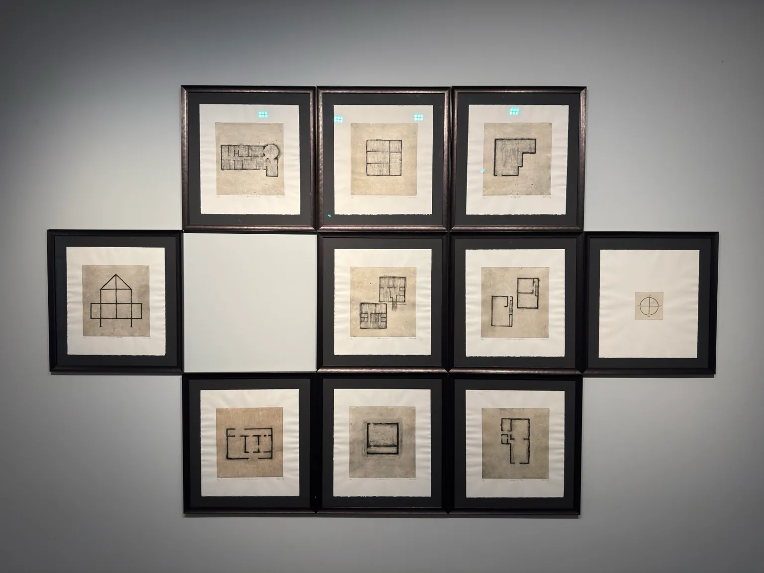 Ten black-framed works containing geometric and architectural line drawings arranged together on a wall at Hayy Jameel.