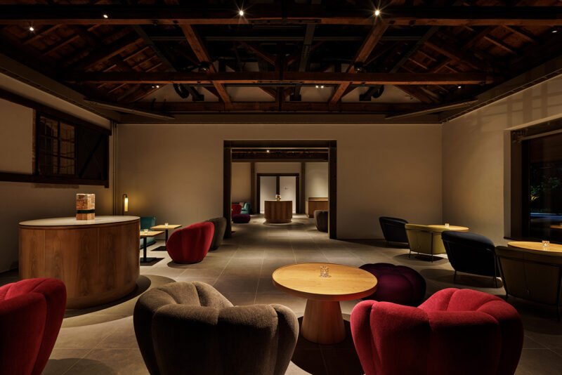 Dining lounge with low seating, circular tables and a dark exposed overhead structure
