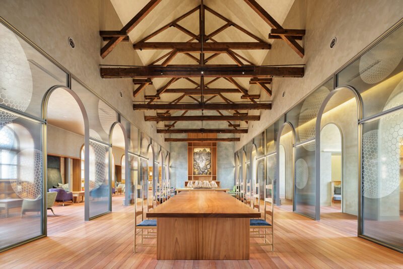 Long main lounge with repeated arches, exposed roof structure and timber furniture
