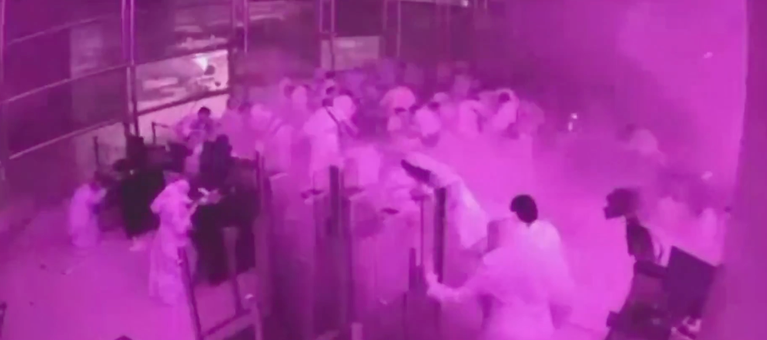Passengers moving through an airport terminal amid smoke. Screenshot from Al Arabiya. | مسافرون يتحركون داخل صالة المطار وسط الدخان. لقطة شاشة من قناة العربية.