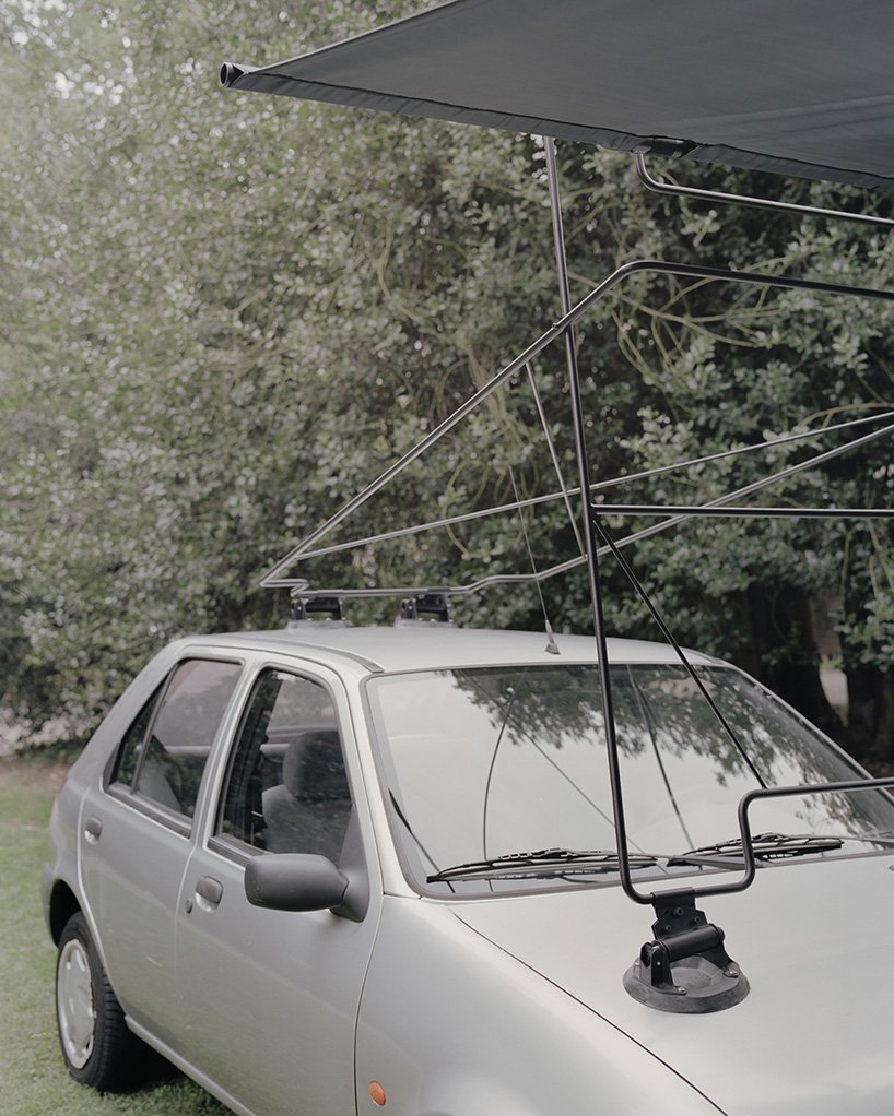 Slender metal members connect the overhead assembly to the silver car.