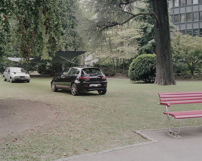 Two cars and a suspended sheet define an open space within the lawn.
