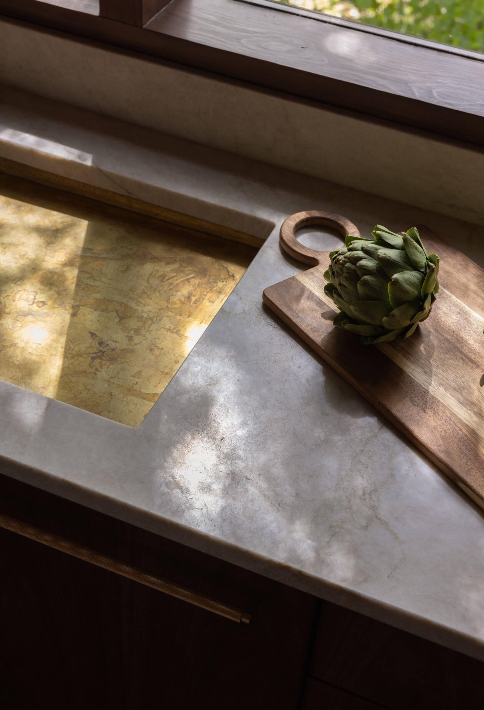 The sink and draining surface combine brass and pale stone
