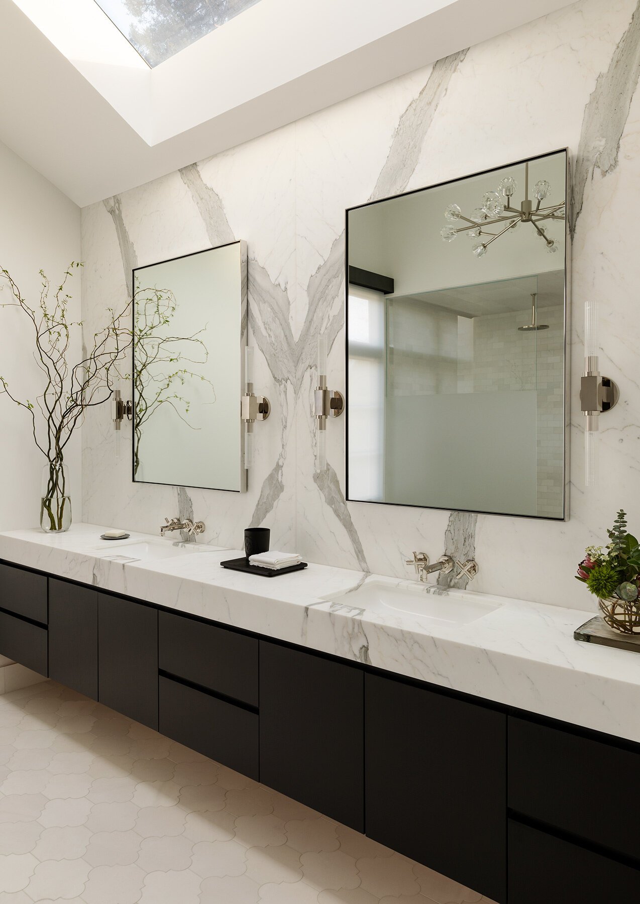 Dark vanity cabinetry contrasts with the veined stone wall.