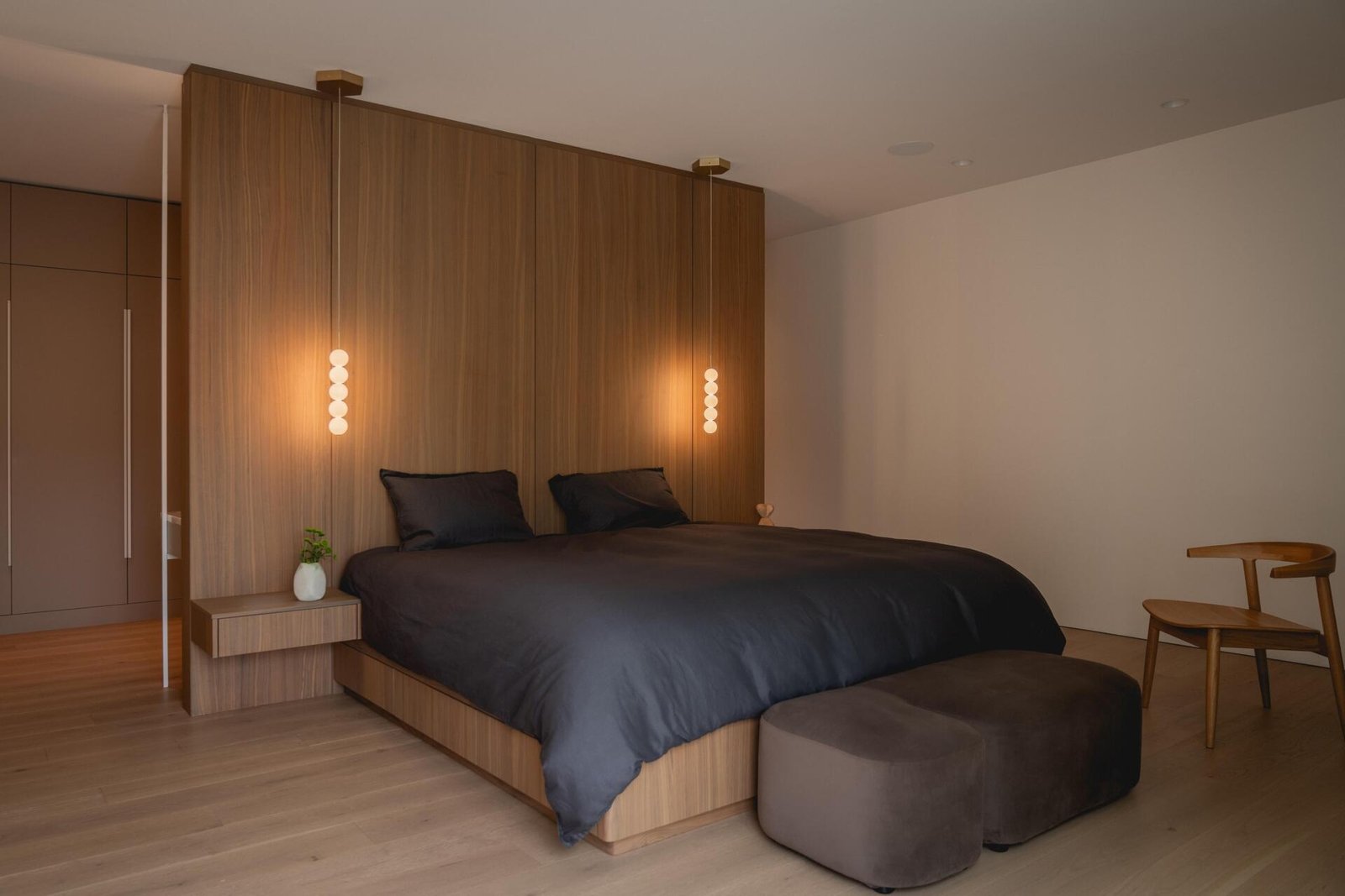 The primary bedroom uses walnut paneling and integrated bedside tables.