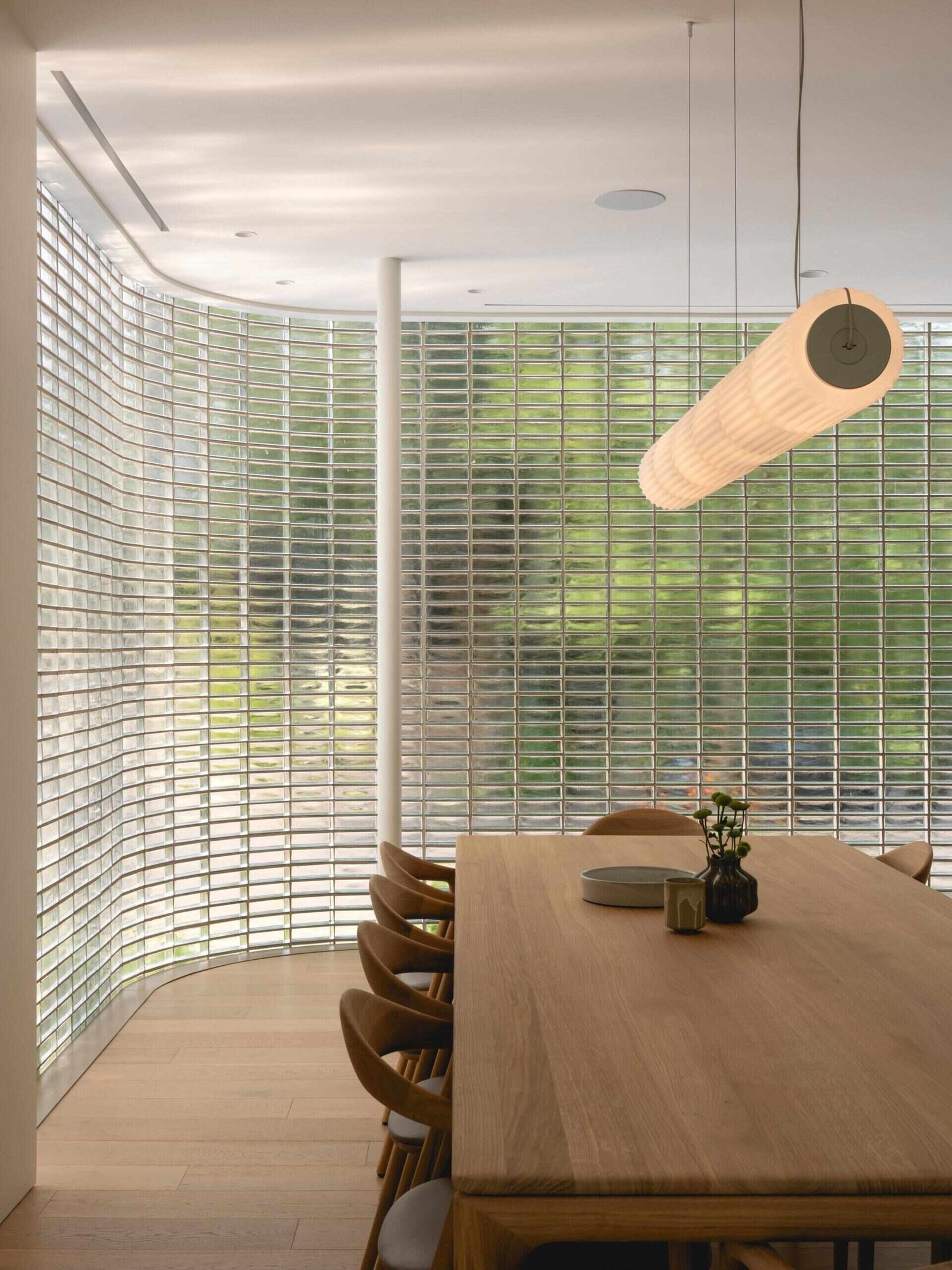 The dining table stands beside the curved translucent wall.