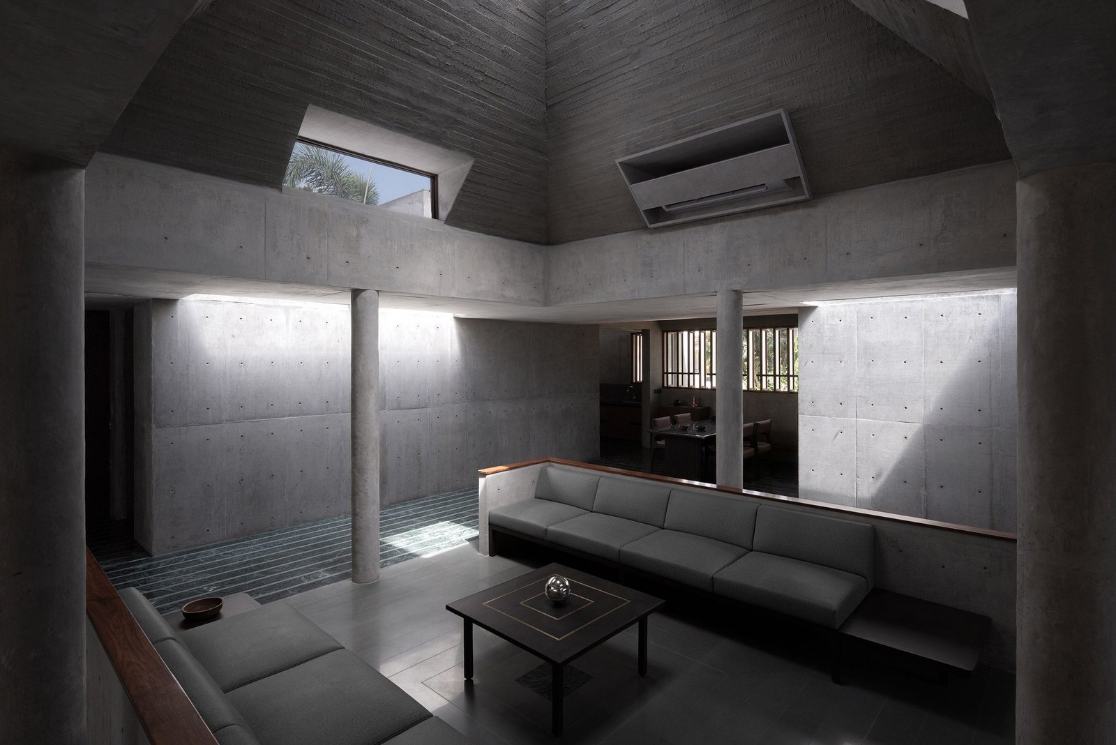 Wide view of Monastic Field&rsquo;s central living space with clerestory light on exposed concrete walls