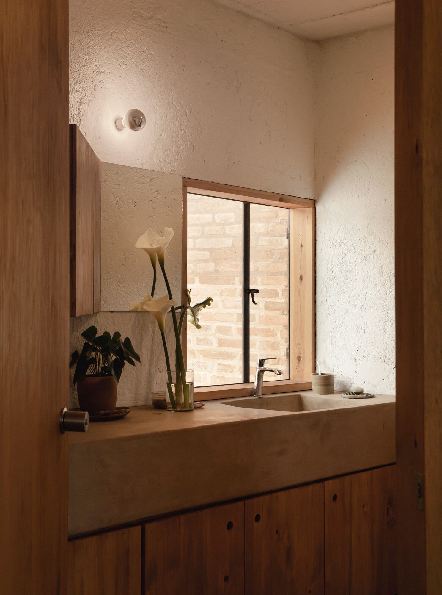The bathroom window looks into a small planted space bounded by exposed brick.