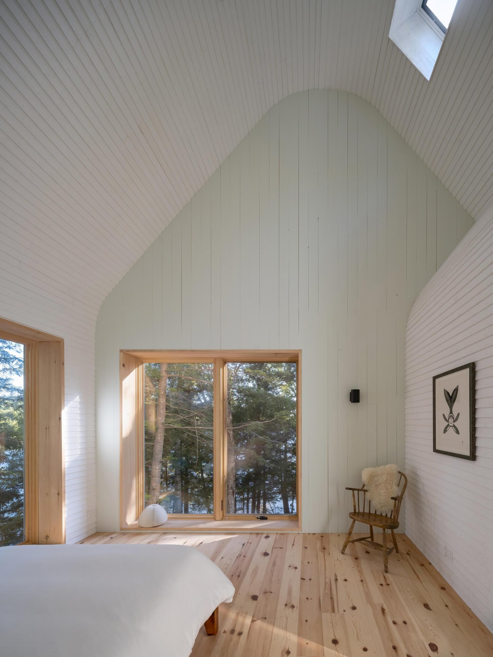 Primary bedroom with pale green gable wall and woodland views